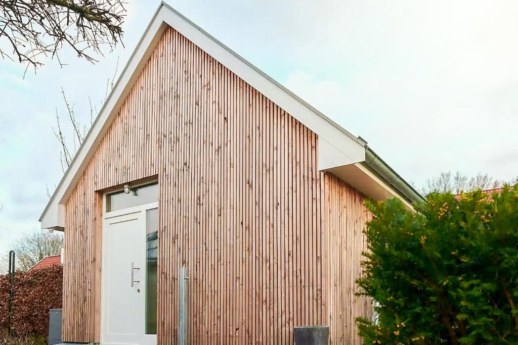 ein großes Holzgebäude mit einer weißen Tür in der Unterkunft Ferienwohnung „Langer Jammer“ im Hesterhoff in Bad Zwischenahn