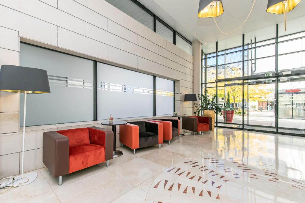 - un hall avec des chaises rouges, un lit et des fenêtres dans l'établissement Residhome Val d'Europe, à Montévrain