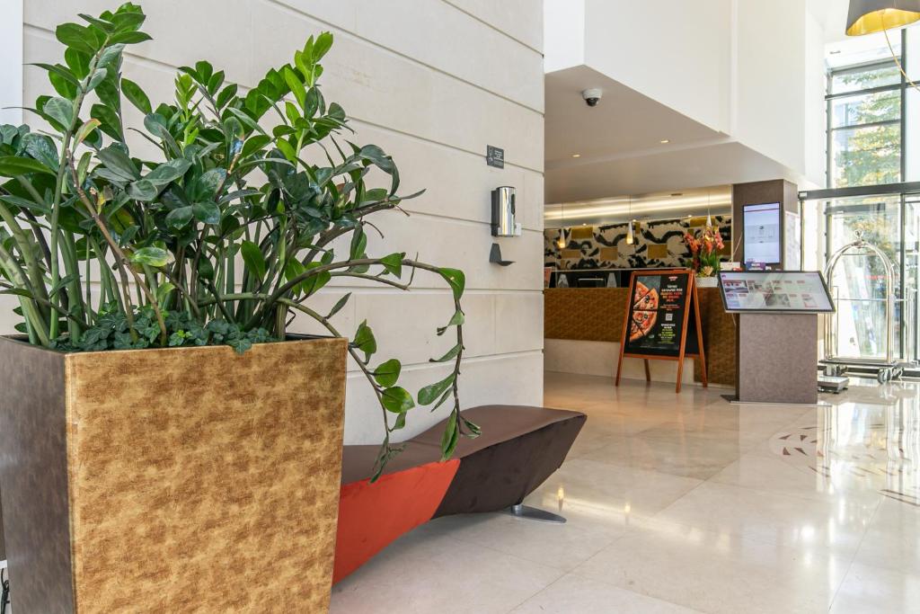 un hall avec deux grandes plantes en pot dans un bâtiment dans l'établissement Residhome Val d'Europe, à Montévrain