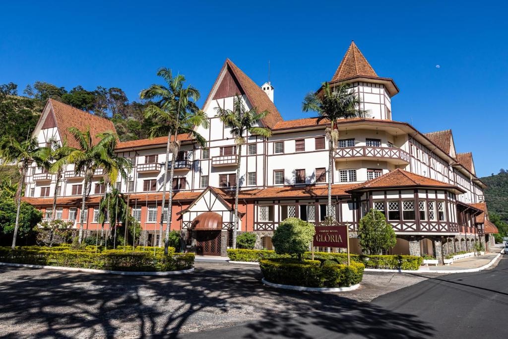 a large building with palm trees in front of it at Grande Hotel Glória in Águas de Lindoia