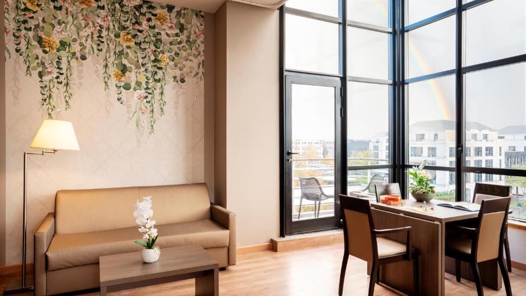 a living room with a couch and a table and chairs at Residhome Val d'Europe in Montévrain