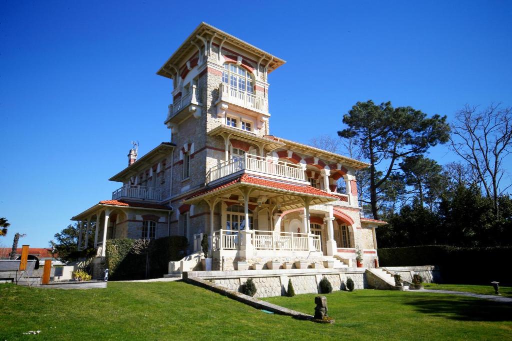 une grande maison avec une tour au sommet d'une pelouse dans l'établissement Villa La Tosca, à Lanton