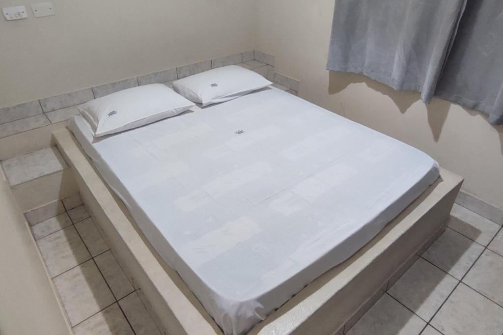 a white bed sitting in a room at Hotel Gringos in Londrina