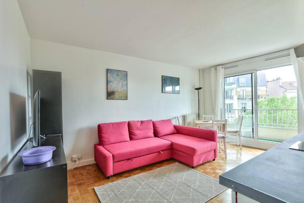- un canapé rose dans le salon doté d'une fenêtre dans l'établissement Lovely 1 BR Flat with balcony near metro line 10, à Boulogne-Billancourt