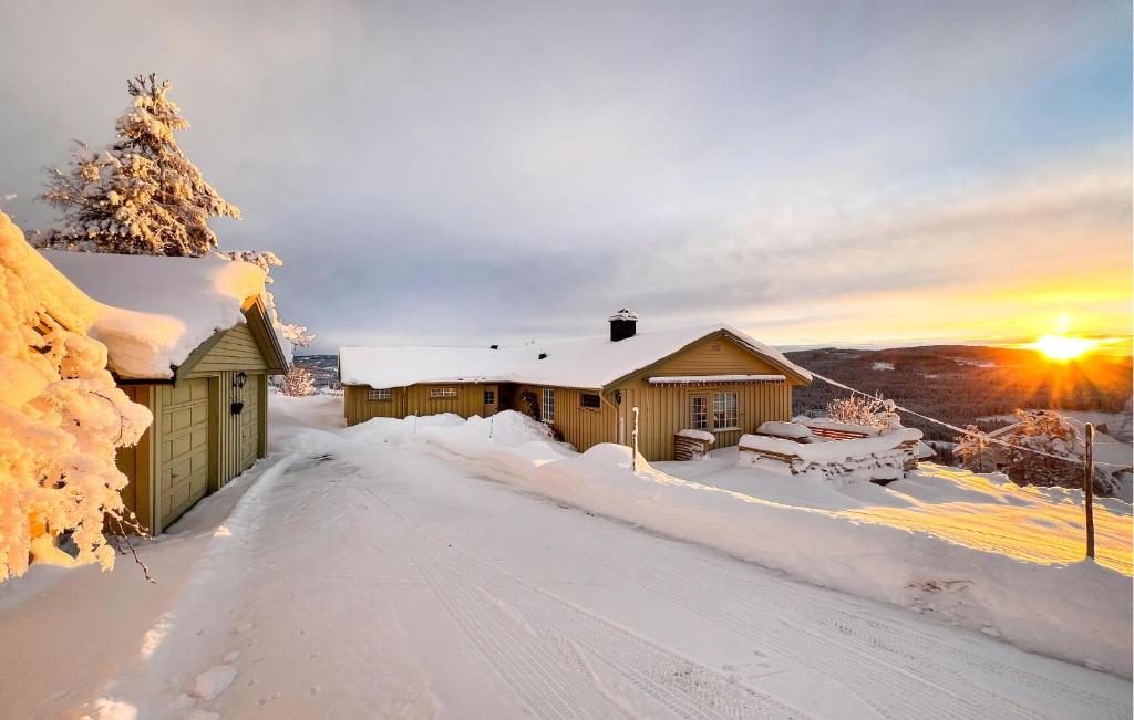 a cabin in the snow with the sunset in the background at Stunning Home In Svingvoll With House A Mountain View in Svingvoll