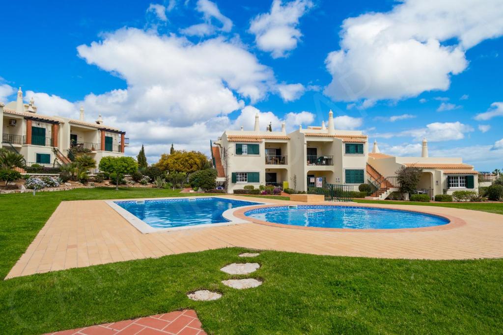 a villa with a swimming pool in front of a house at Carvoeiro Apartment 7A in Carvoeiro