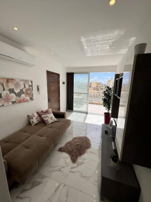 ein Wohnzimmer mit einem braunen Sofa und einem TV in der Unterkunft 2 Bedroom Apartment in Msida, Malta in Msida