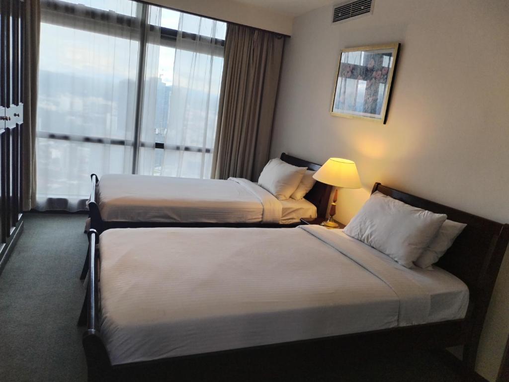 two beds in a hotel room with a window at KL MARIGOLD APARTMENT At TIMES SQUARE in Kuala Lumpur