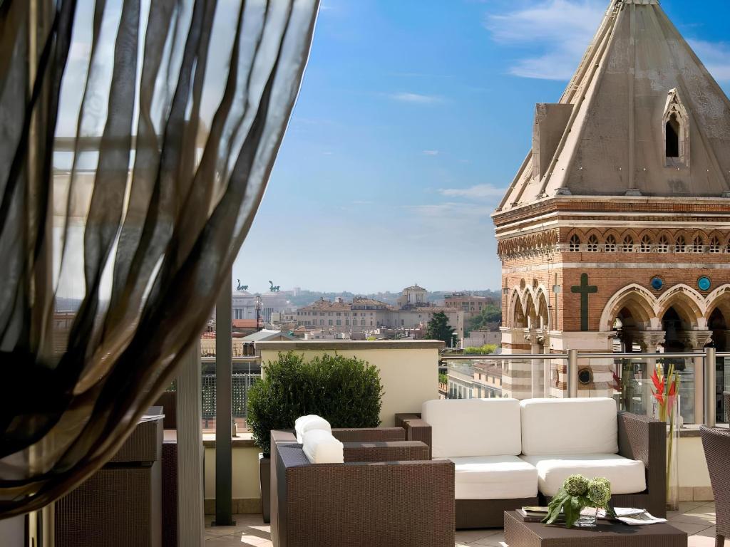 Una vista desde el balcón de un edificio con muebles blancos. en La Griffe Hotel Roma, en Roma