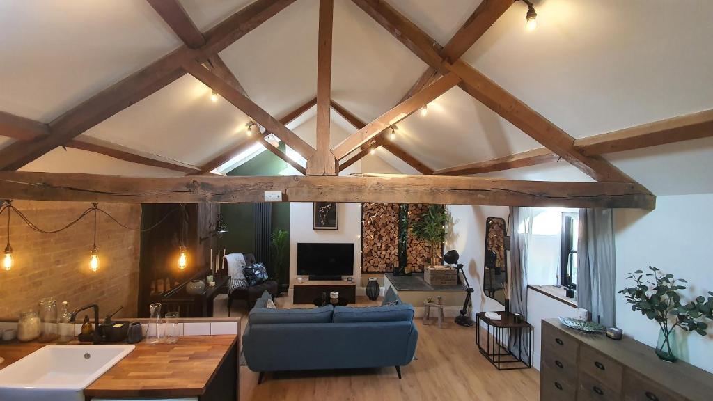 a living room with wooden ceilings and a blue couch at A countryside retreat in Chipping Norton