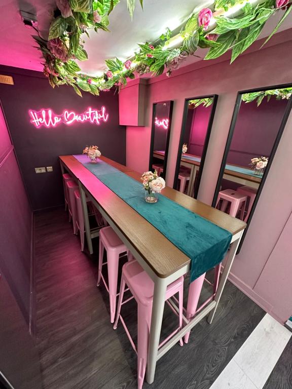 a dining room with a table and pink walls at The Ultimate Hen Suite with Bar & Makeup Room in Manchester