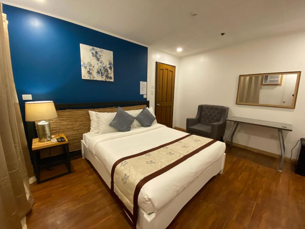 ein Schlafzimmer mit einem großen Bett und einer blauen Wand in der Unterkunft The New View by Ecotel in Iloilo City