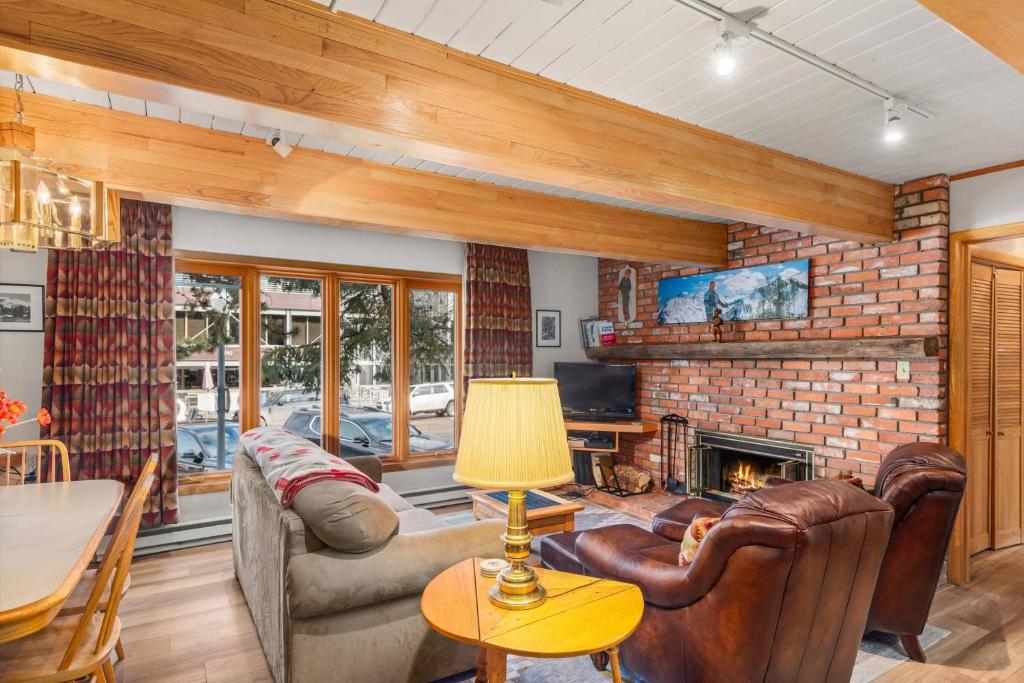 a living room with leather furniture and a brick fireplace at Chateau DuMont 05 in Aspen