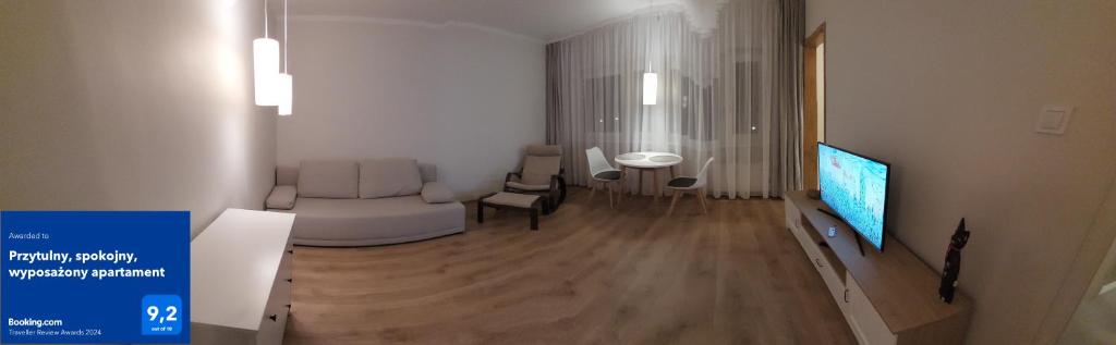 sala de estar con TV, sofá y mesa en Przytulny, spokojny, wyposażony apartament, en Poznan