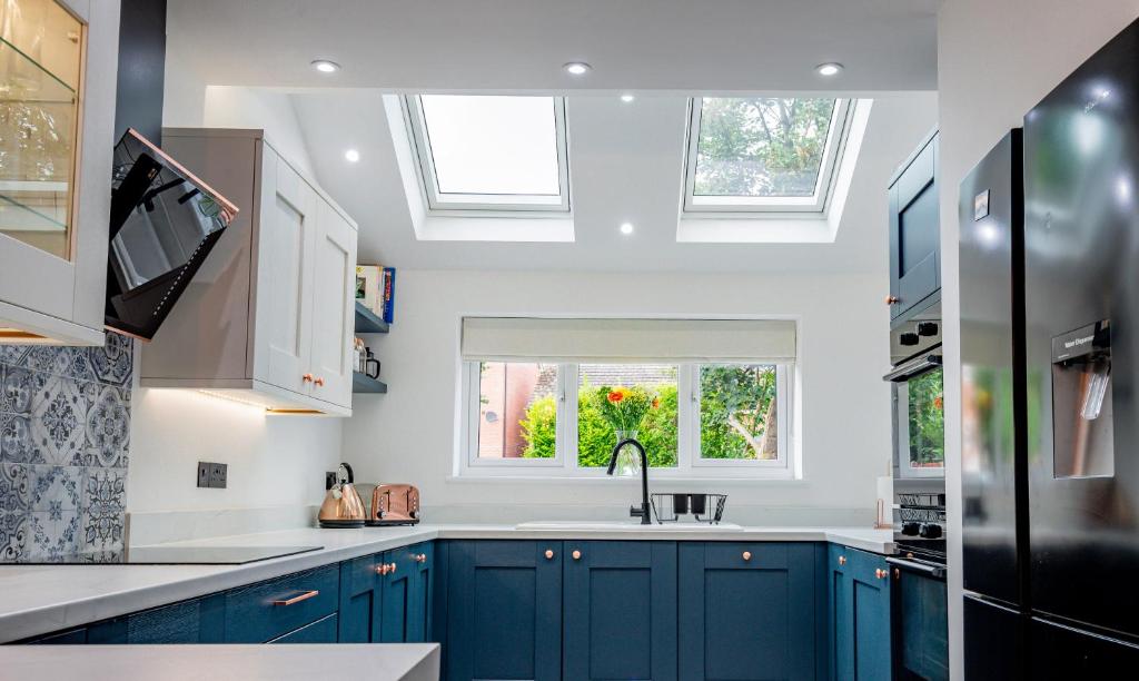 uma cozinha com armários azuis, um lavatório e janelas em Exquisite renovation in central location em Hereford