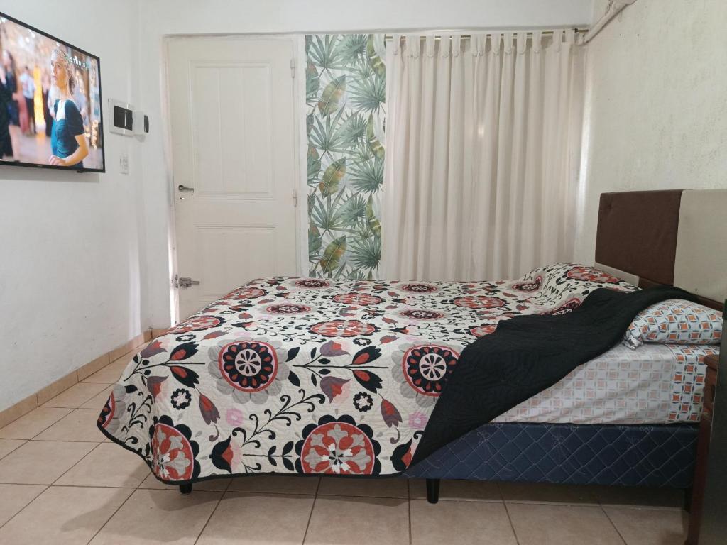 a bedroom with a bed with a flowered comforter at Monoambiente pequeño in Bahía Blanca