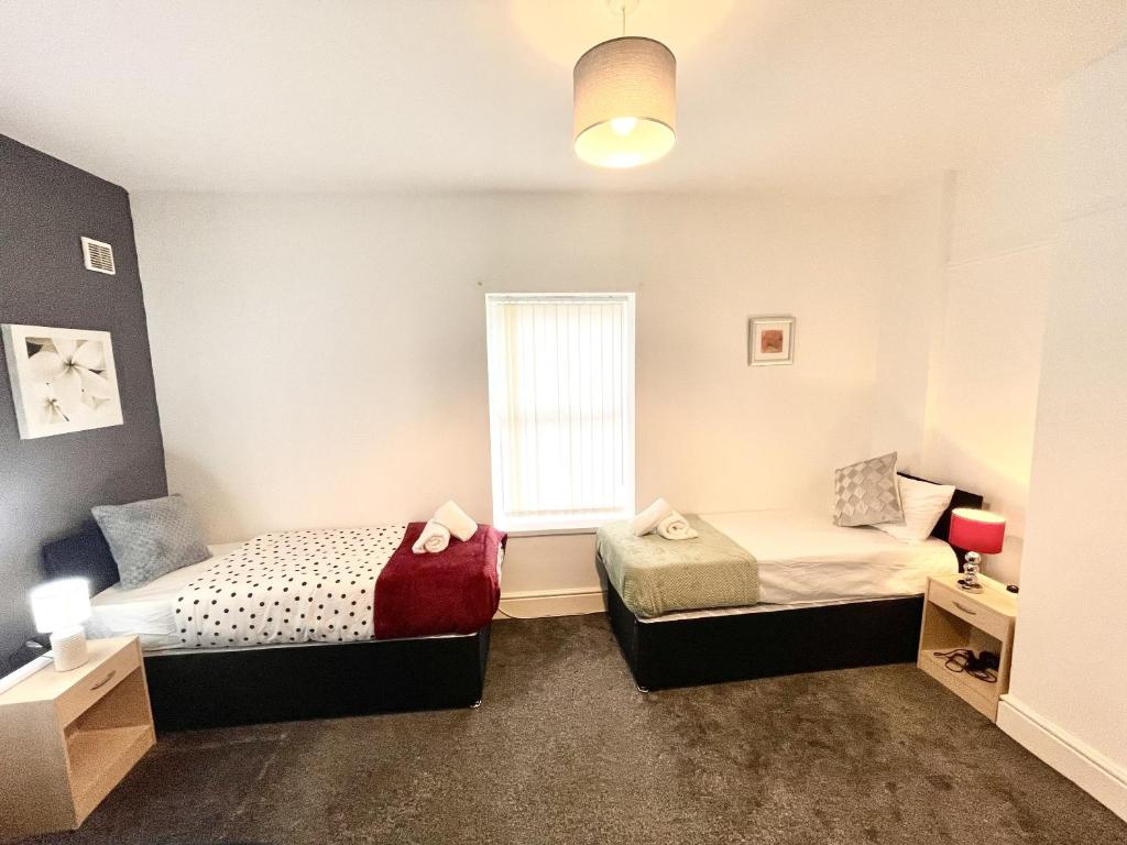 a bedroom with two beds and a window at Beautiful Mordern Apartment with Bathroom in Seacombe