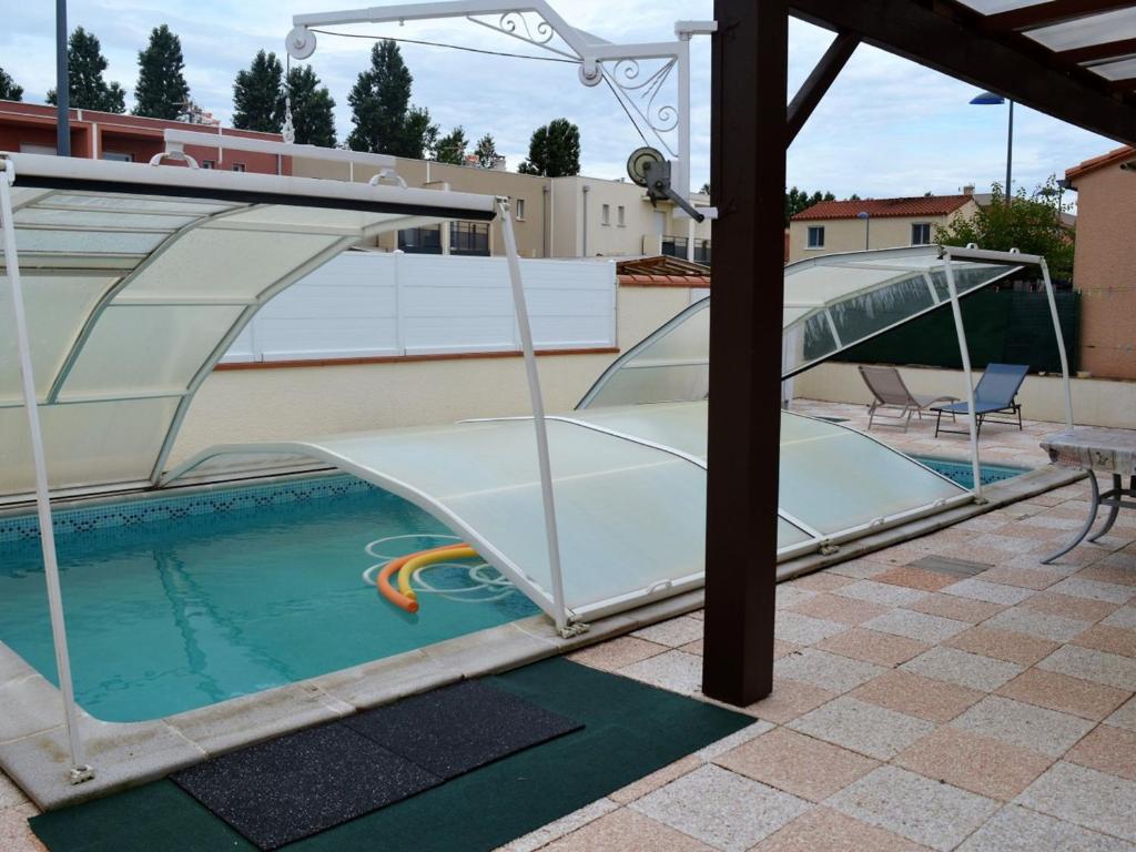 uma piscina com uma cobertura de vidro e um escorrega em Maison Argelès-sur-Mer, 3 pièces, 7 personnes - FR-1-225-789 em Argelès-sur-Mer