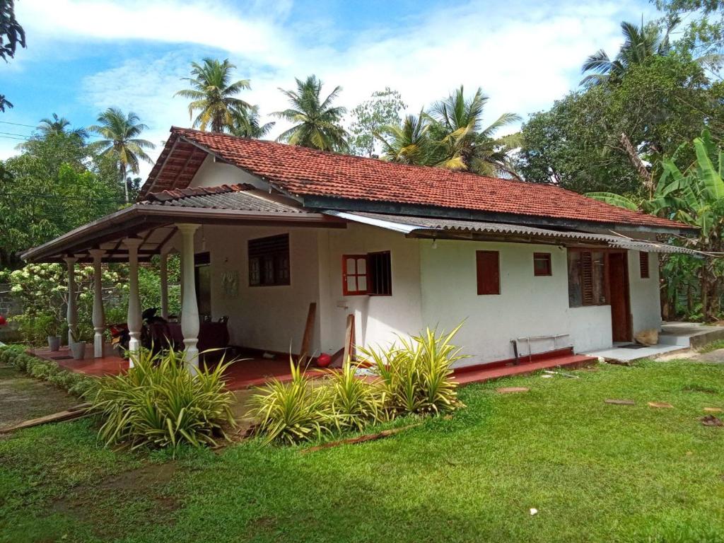 a small white house with a grass yard at Villa Samudra Hikkaduwa in Hikkaduwa