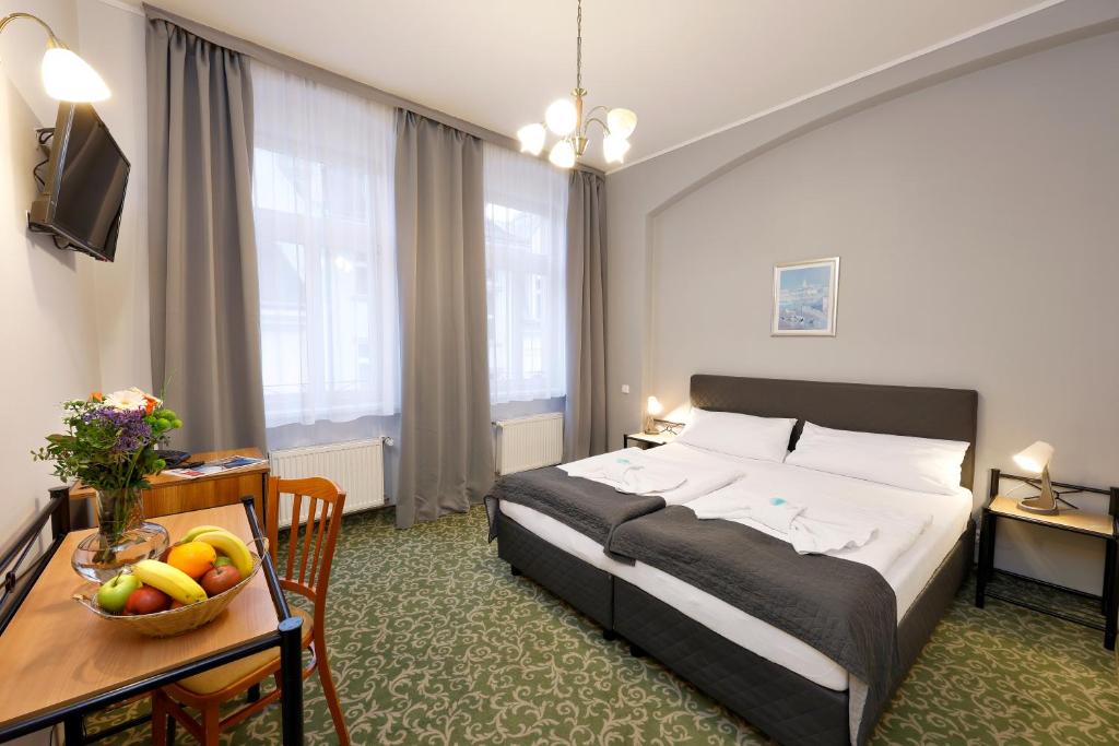 a hotel room with a bed and a table with a bowl of fruit at Hotel Boston in Karlovy Vary