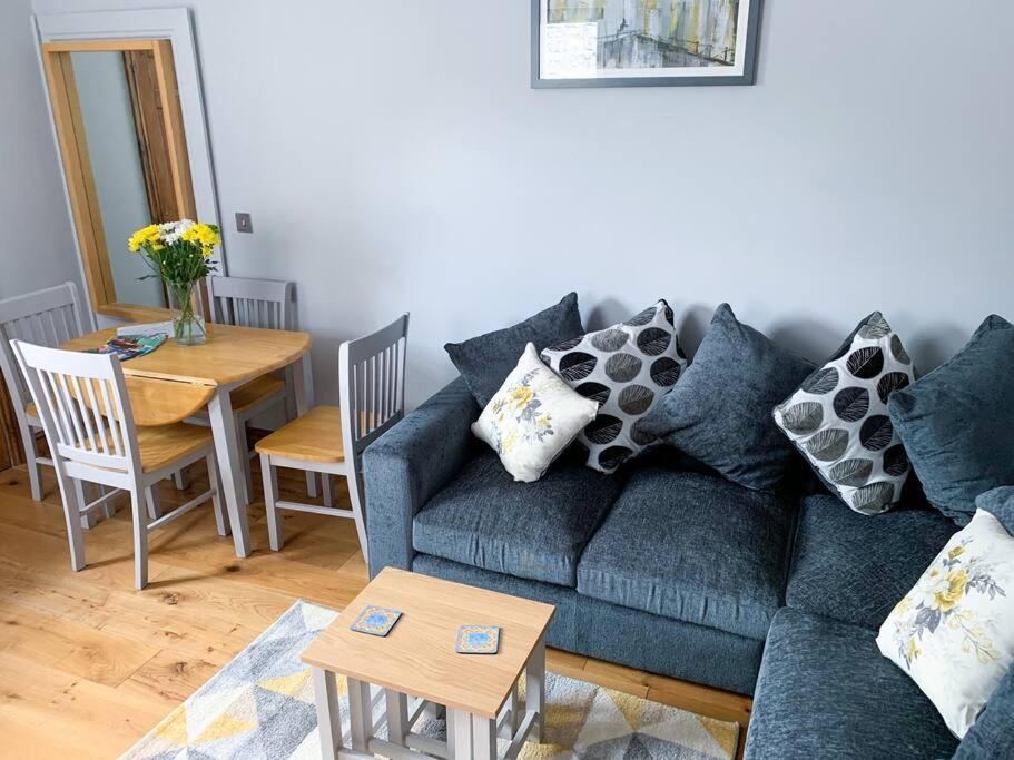 a living room with a blue couch and a table at Cosy annex in the gateway to the lakes in Burneside