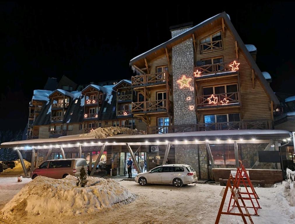 a building with a car parked in front of it at Apartman 452 sa pogledom na stazu Hotel Vučko private host in Jahorina