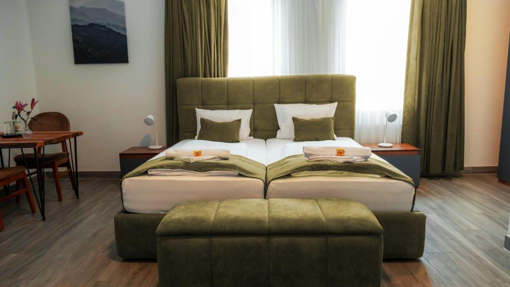 a bedroom with a large bed and a ottoman at E&B Aparthotel in Korb
