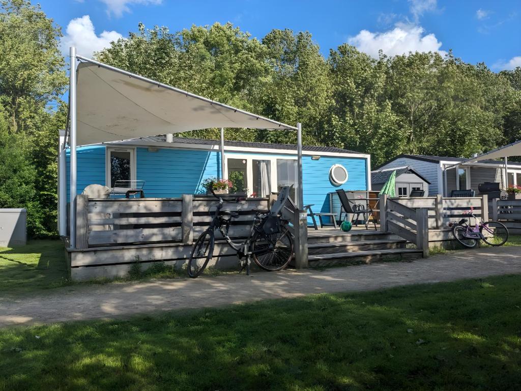 Cozy Tiny SolHouse 7 - Near Groningen - 5 Star Location في Kropswolde: القافلة الزرقاء مع الدراجات متوقفة أمامه