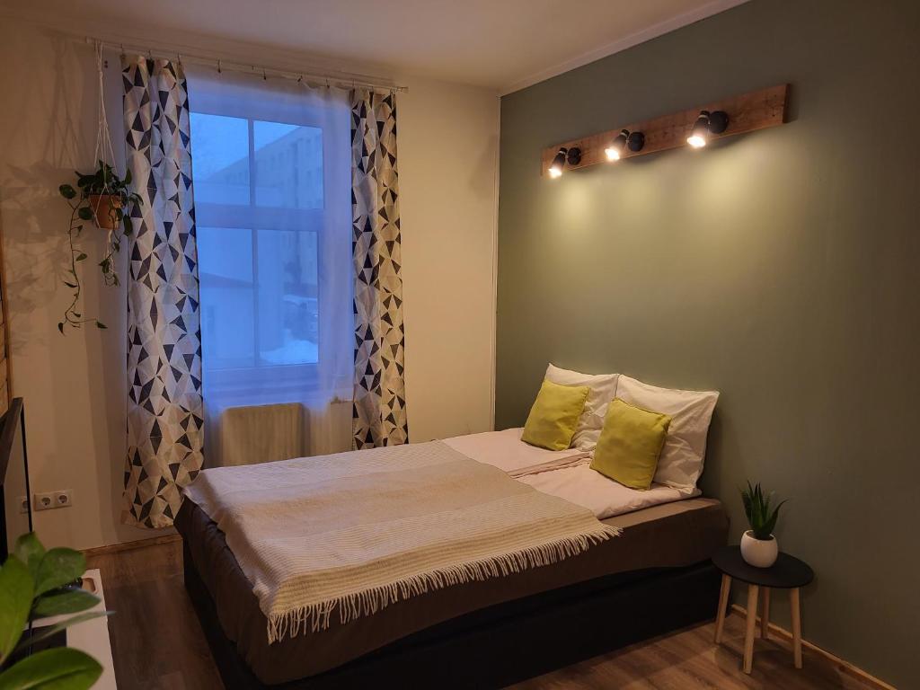 a bedroom with a bed with green pillows and a window at Old Town Apartment in Valga