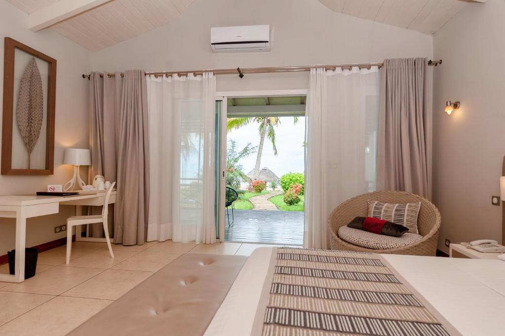 a bedroom with a bed and a desk and a window at Palm Beach Resort & Spa in Ambondrona