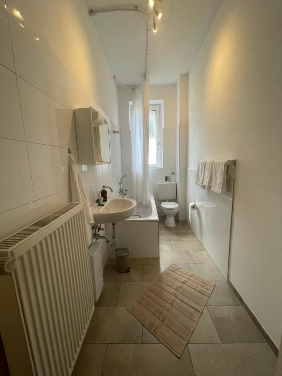 a white bathroom with a sink and a toilet at Altbauwohnung mit 2 Balkonen in Wuppertal