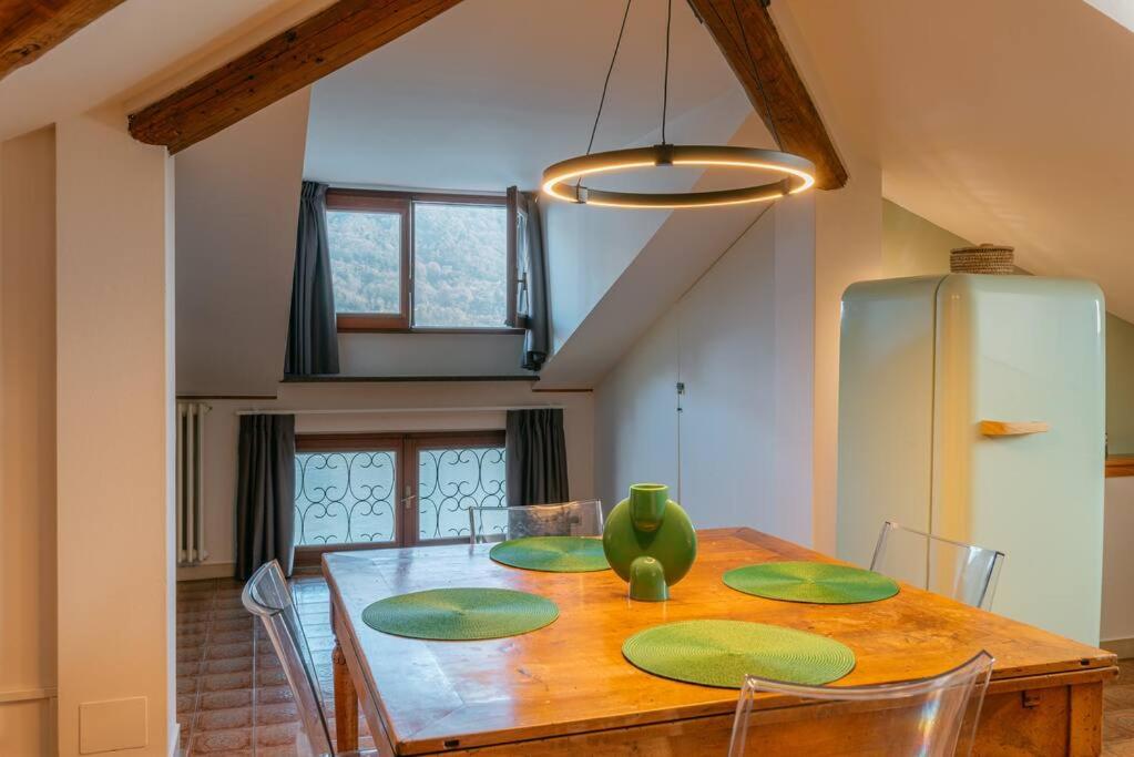 a dining room table with a green vase on it at Loft Glicine, by R Collection apartment in Brienno