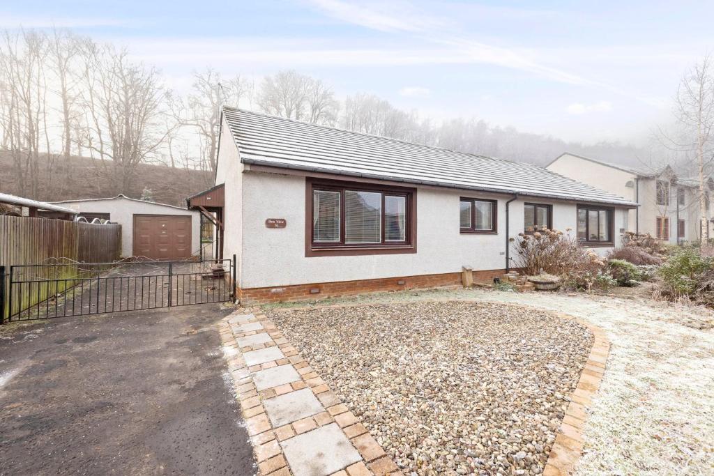 a white house with a fence and a driveway at ALTIDO Beautiful 3bed house with Garden and Parking in Pitlochry