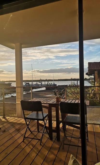 - une terrasse couverte avec une table et deux chaises et une vue sur l'eau dans l'établissement Appartement à l'entrée d'Arcachon vue bassin, à La Teste-de-Buch