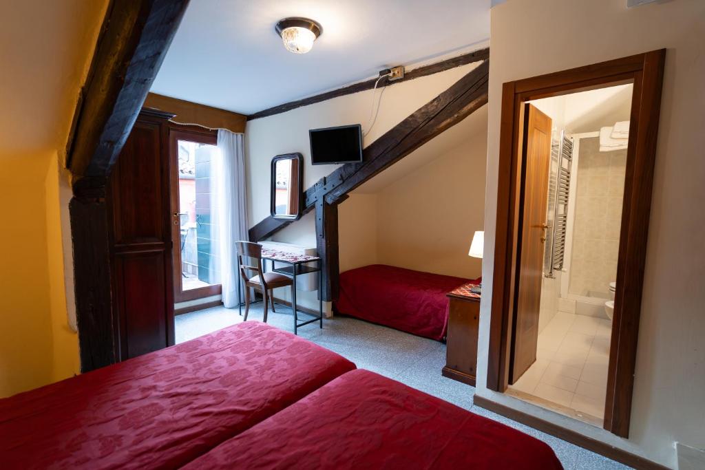 a bedroom with a red bed and a desk at Hotel Tivoli in Venice