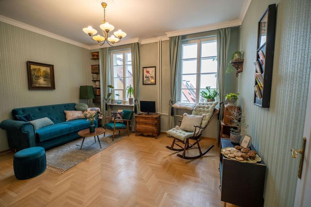 ein Wohnzimmer mit einem blauen Sofa und Stühlen in der Unterkunft Vintage boutique Old Town Warsaw in Warschau
