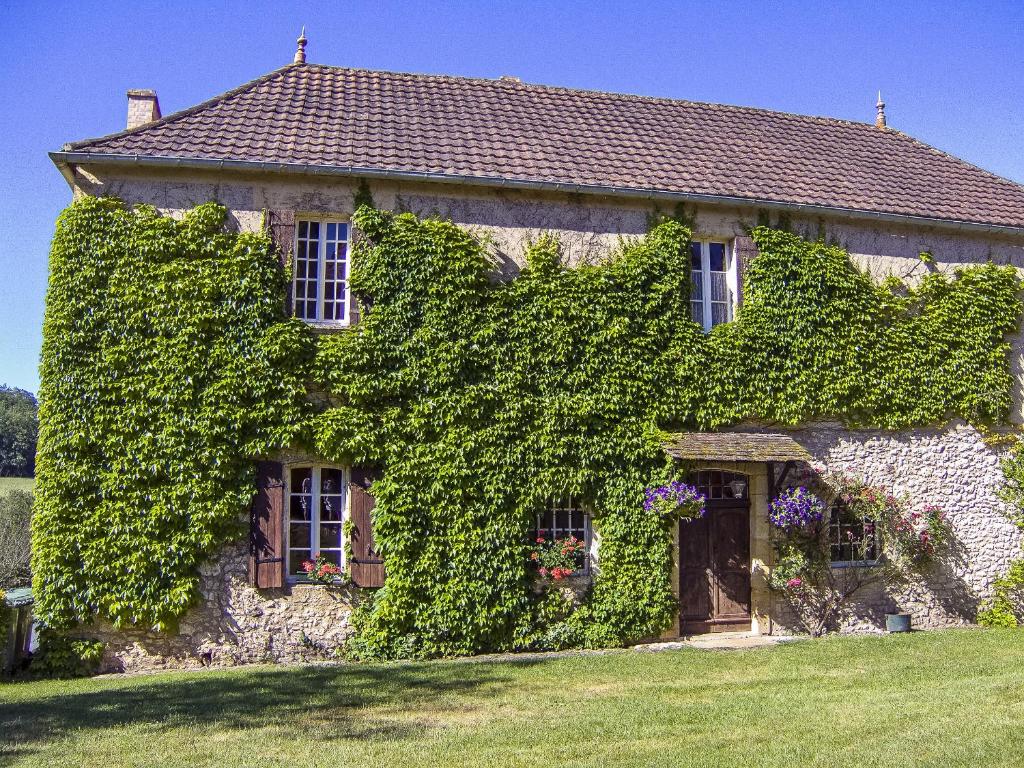 an ivy covered house with a door and windows at Le Manoir De St Marcel in Saint-Marcel-du-Périgord