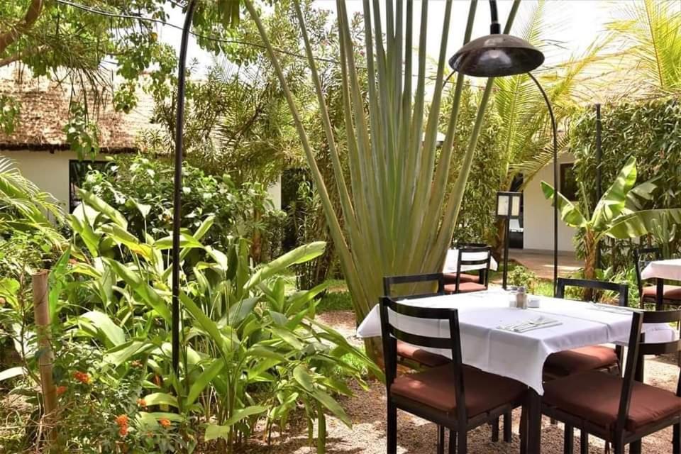 a table and chairs in a garden with plants at Benoua Lodge in Ouagadougou