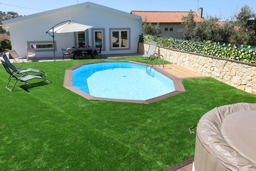 einen Hinterhof mit einem Pool im Gras in der Unterkunft Da Serra guesthouse in Porto de Mós