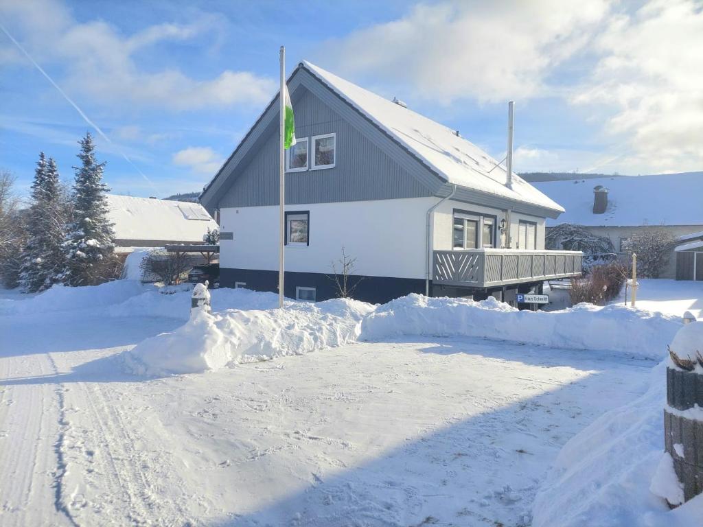 a house is covered in snow with a driveway at Ferienwohnung Haus Schmitt in Winterberg