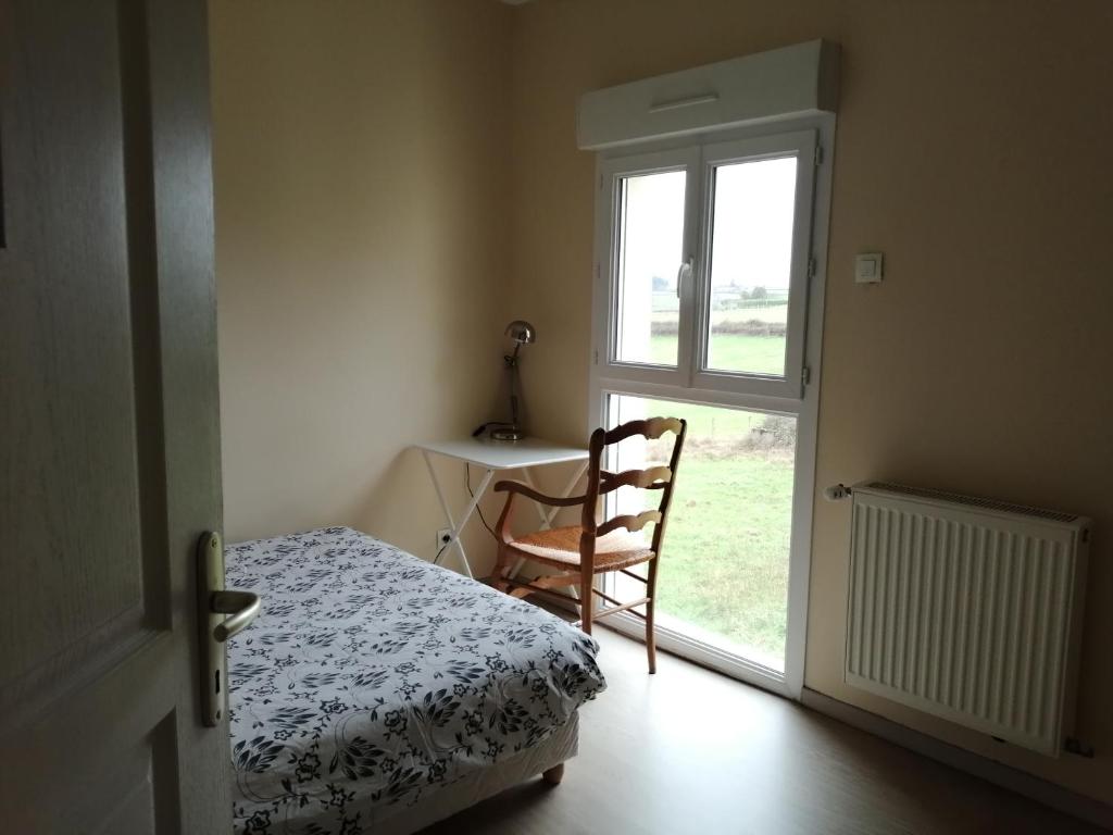1 dormitorio con escritorio y silla junto a una ventana en Chambre campagne uxelloise, en Uxeau
