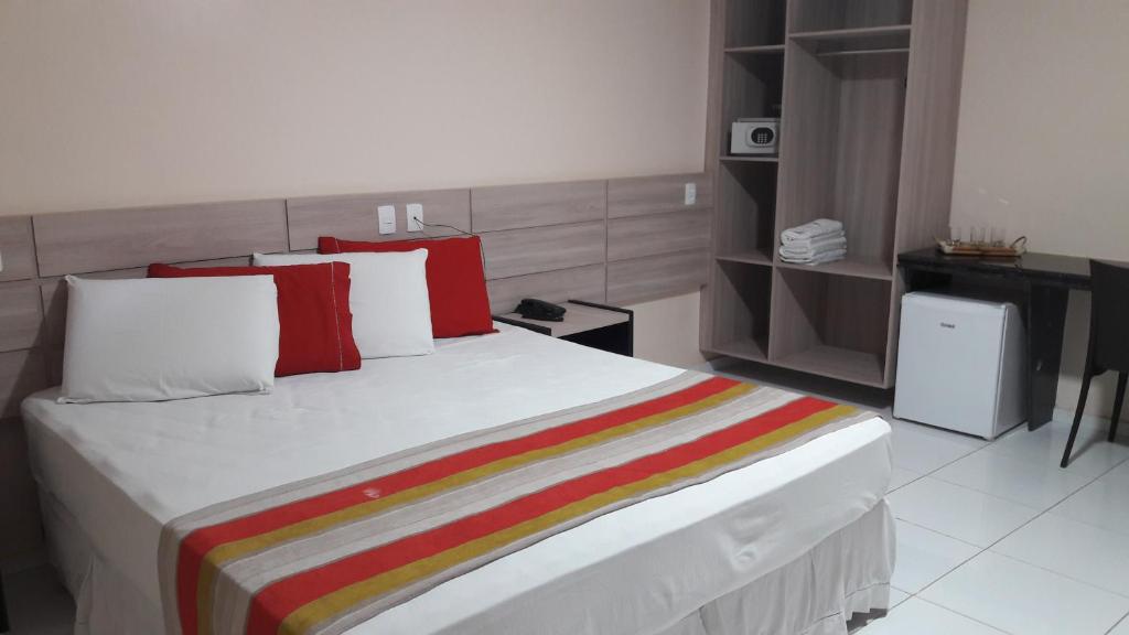 ein Schlafzimmer mit einem großen weißen Bett mit roten Kissen in der Unterkunft MONTERREY HOTEL in Santa Inês