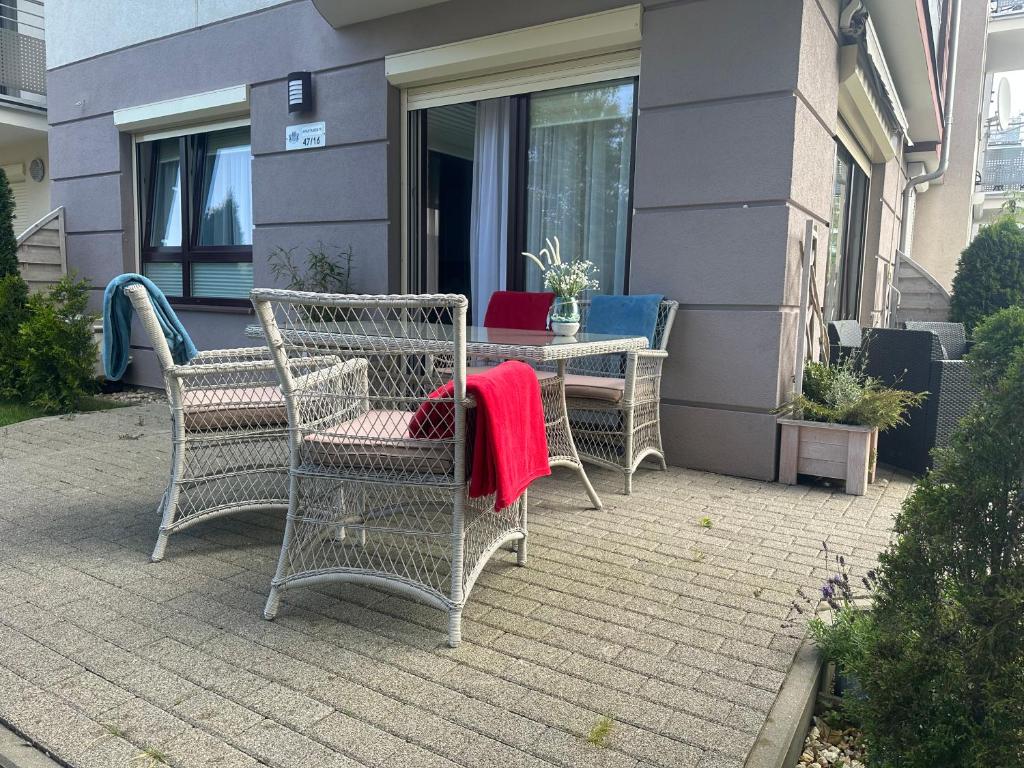 um pátio com cadeiras e uma mesa com um cobertor vermelho em Amko Style Apartamenty Nord 7 z prywatnym ogródkiem Willa Nord em Jastrzebia Gora