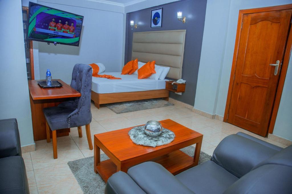 um quarto com uma cama, uma mesa e um sofá em LE GRAND MARIE HOTEL em Dar es Salaam