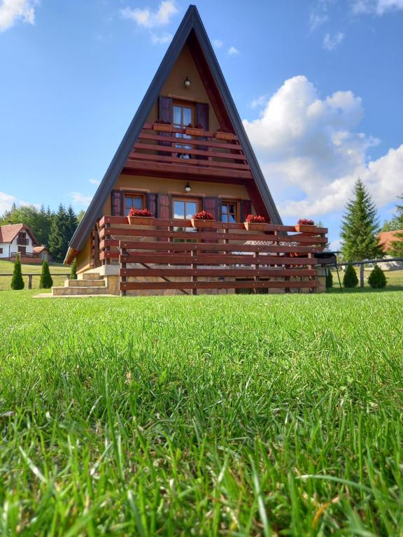 ein Haus mit einem Strohdach auf einem Grasfeld in der Unterkunft Mountain House Tadić 1 in Bajina Bašta