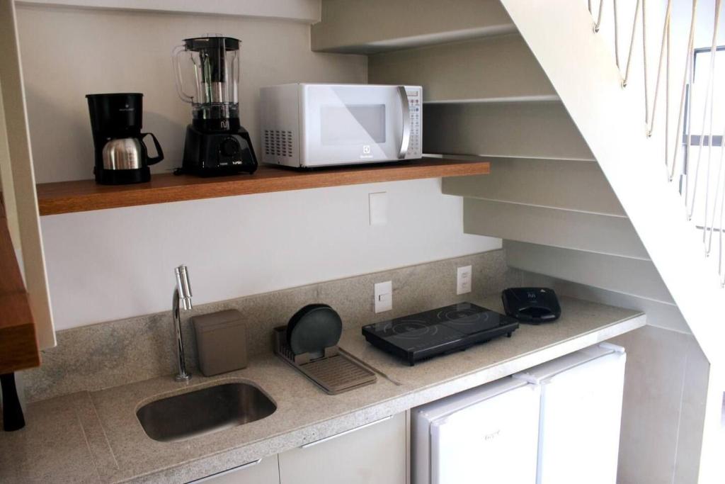 a kitchen counter with a sink and a microwave at APTO 107-Pé na Areia Praia do Maceio - 2 suites, 2 banheiros+SPA Jacuzzi+Roupas de cama in São Miguel do Gostoso