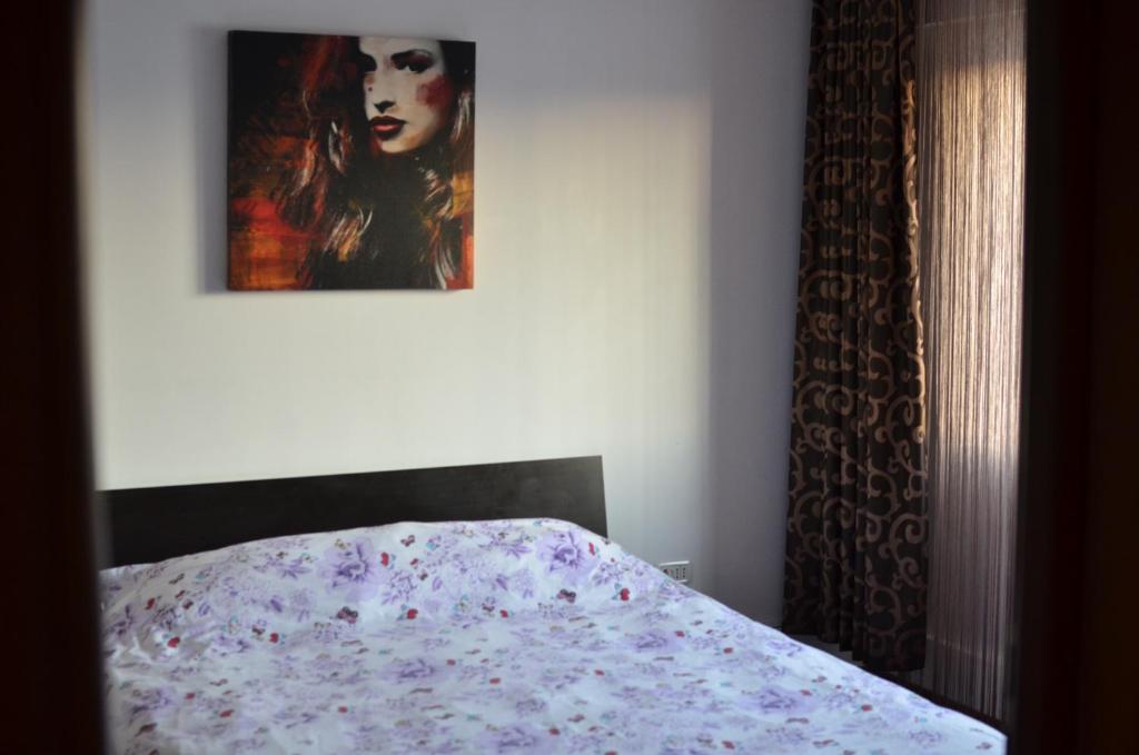 Cozy apartment 2 rooms Prelungirea Ghencea في Bragadiru: غرفة نوم بسرير مع لوحة على الحائط