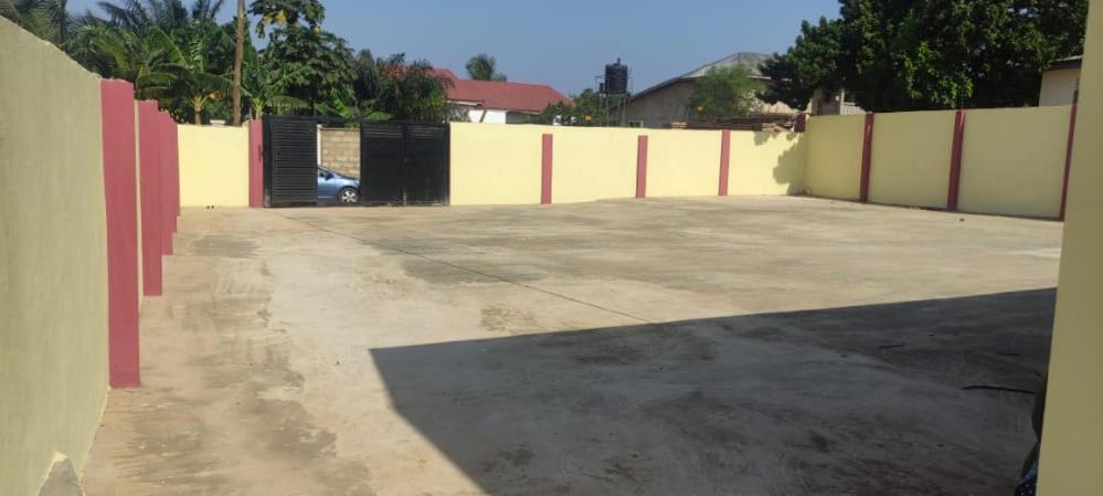 ein leerer Parkplatz mit Zaun und Auto in der Unterkunft Frafraha Cottage in Accra