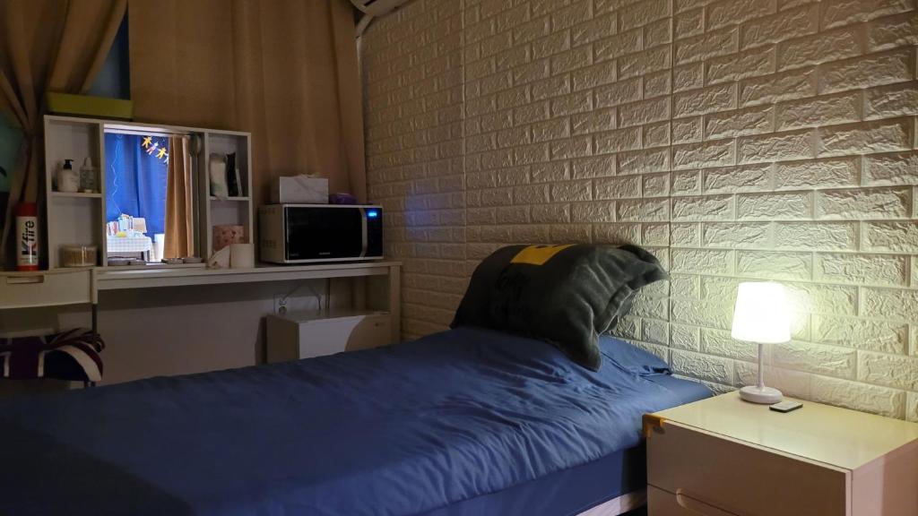 a bedroom with a blue bed and a brick wall at Lion's home 외국인 전용 in Seoul