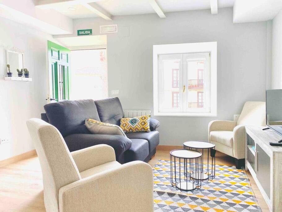a living room with a blue couch and two chairs at Apartamento Bolingas in Comillas